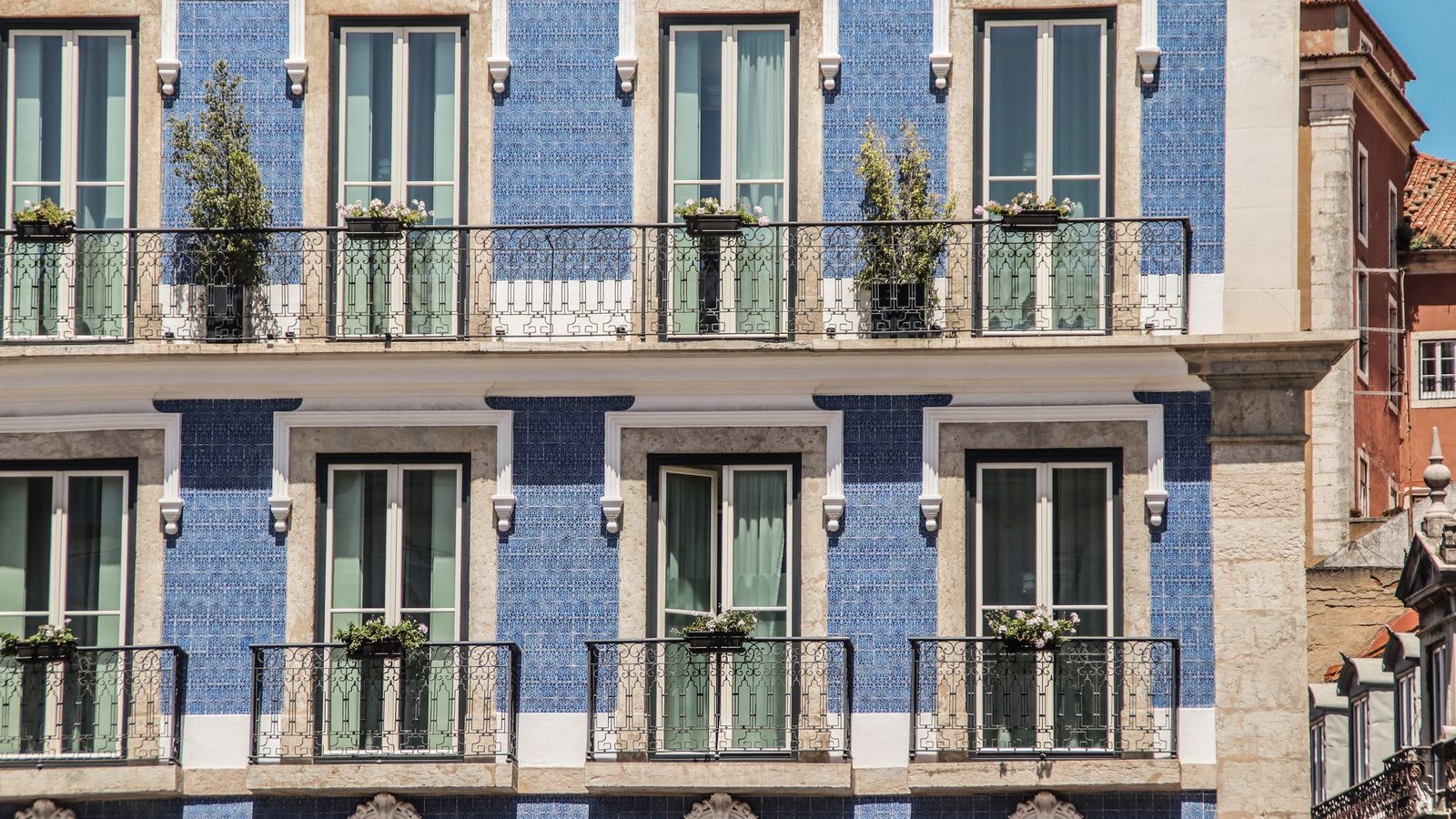 Fachada de um prédio de habitação em Lisboa revestida a azulejo azul, com janelas de sacada, varandas de ferro forjado e cantaria de pedra. Imagem ilustrativa, não é um imóvel analisado pela Rivesta.